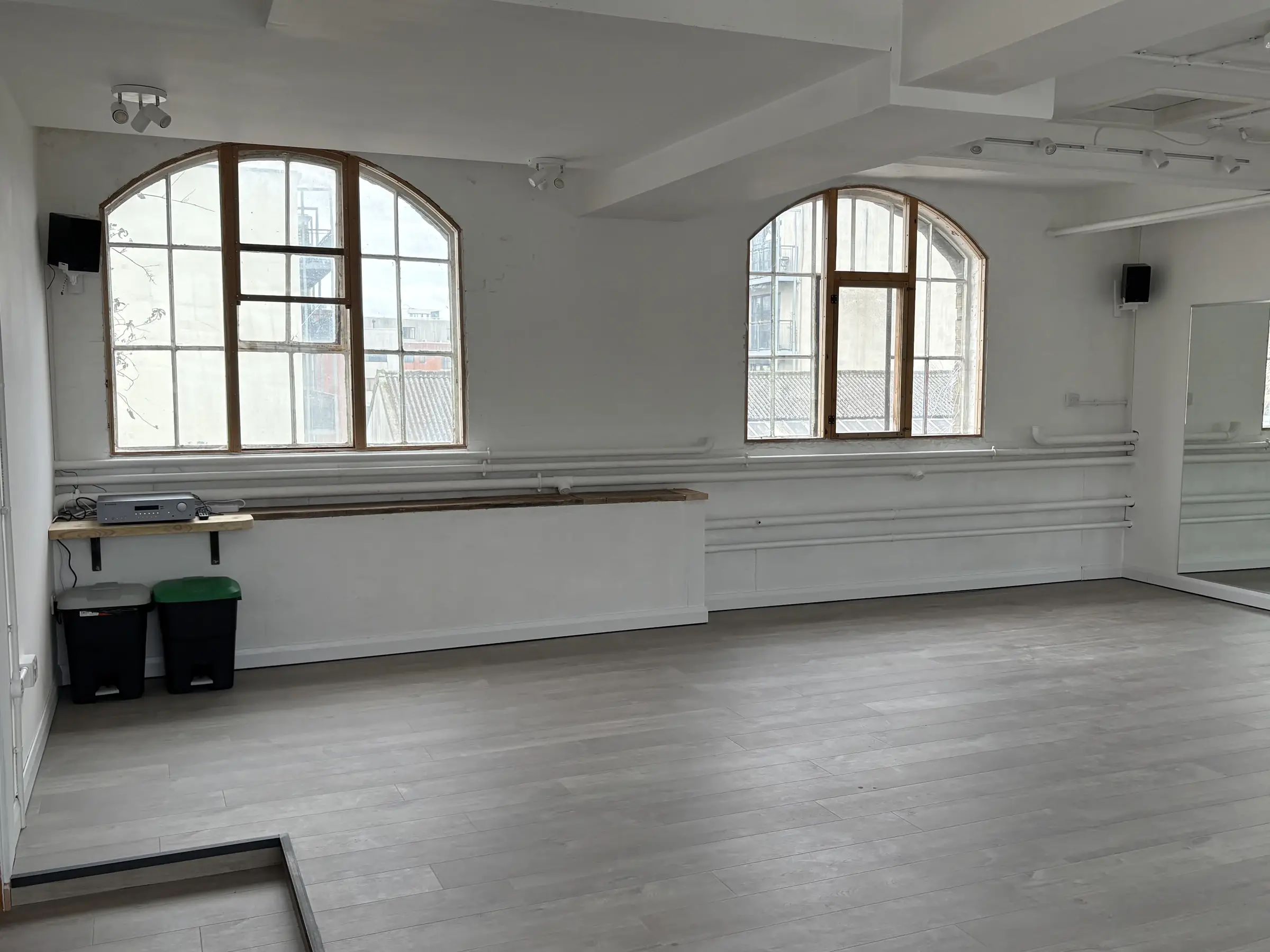 Studio 49 — timber floor and full-height mirrors, natural light from the arched warehouse windows